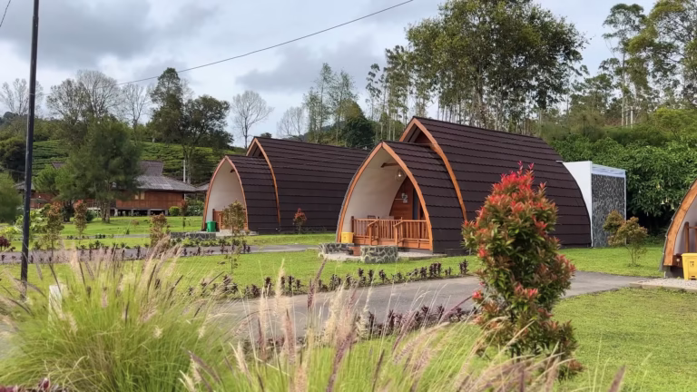Kabin kayu bergaya Hobbit di Kiara Resort, Ciwidey, dengan latar belakang kebun teh hijau dan pegunungan.